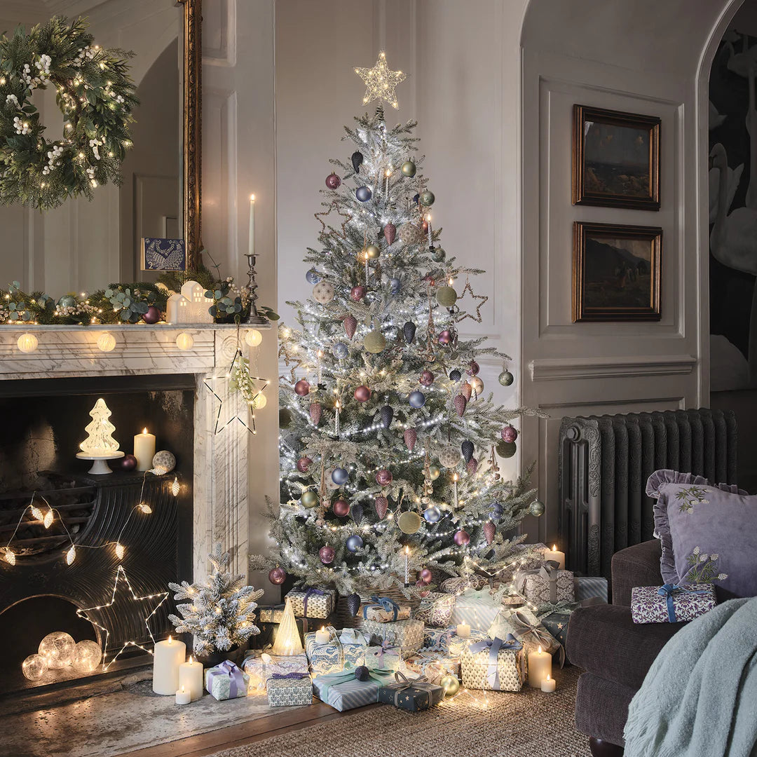 Weihnachtsbaum mit silbernen LED-Kerzen, Kugeln und Lichterketten in festlich dekoriertem Wohnzimmer