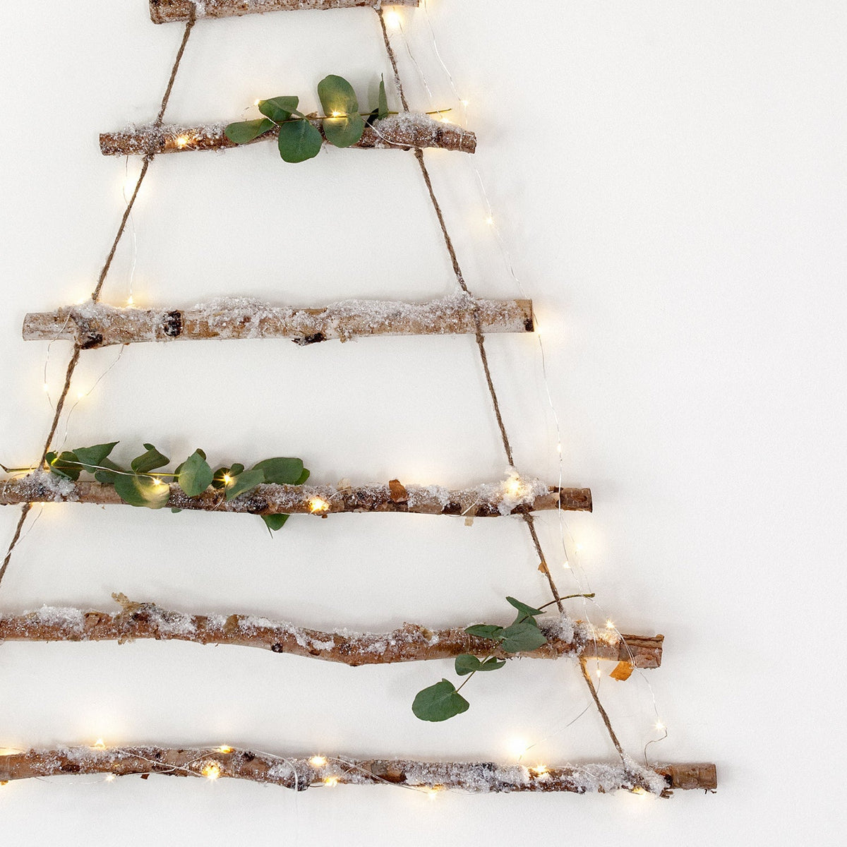 Nahaufnahme der Birkenbaum Deko mit Glitzerschnee, grünen Blättern und warmweißer Micro Lichterkette