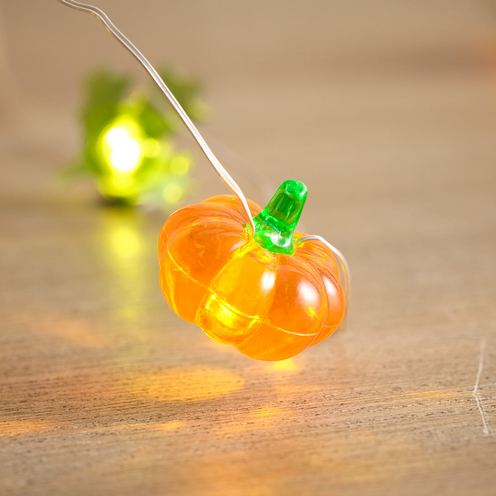 Nahaufnahme eines leuchtenden orangefarbenen Kürbisses aus Kunststoff an Lichterkette