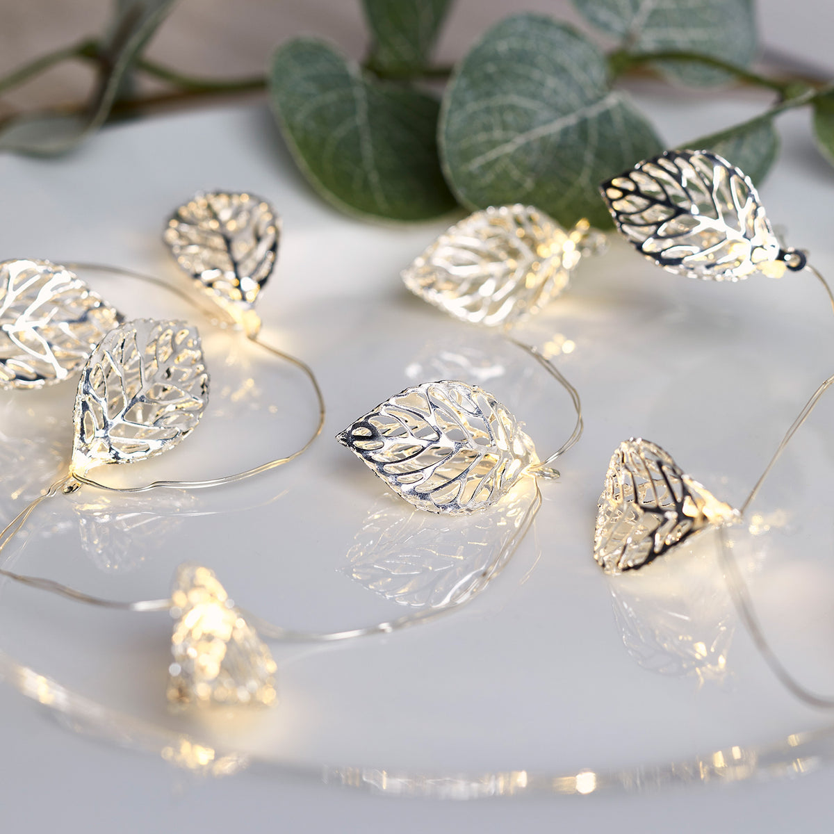 Micro Lichterkette mit 20 silbernen Blättern und warmweißen LEDs auf weißem Untergrund