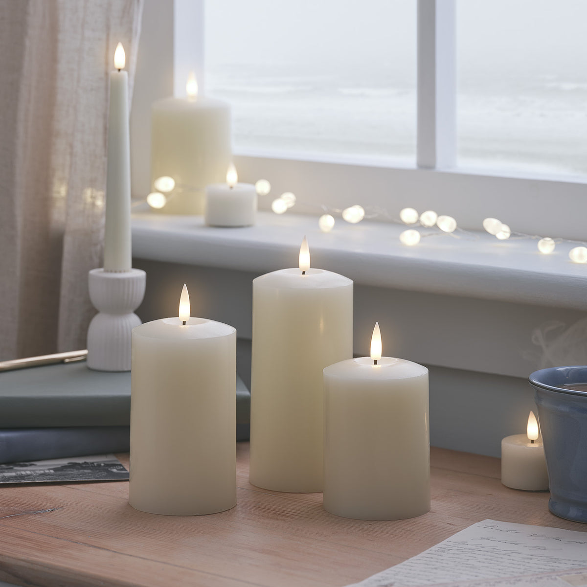 Drei LED-Kerzen auf dunklem Holztisch mit Kristallgläsern und Amethyst-Steinen
