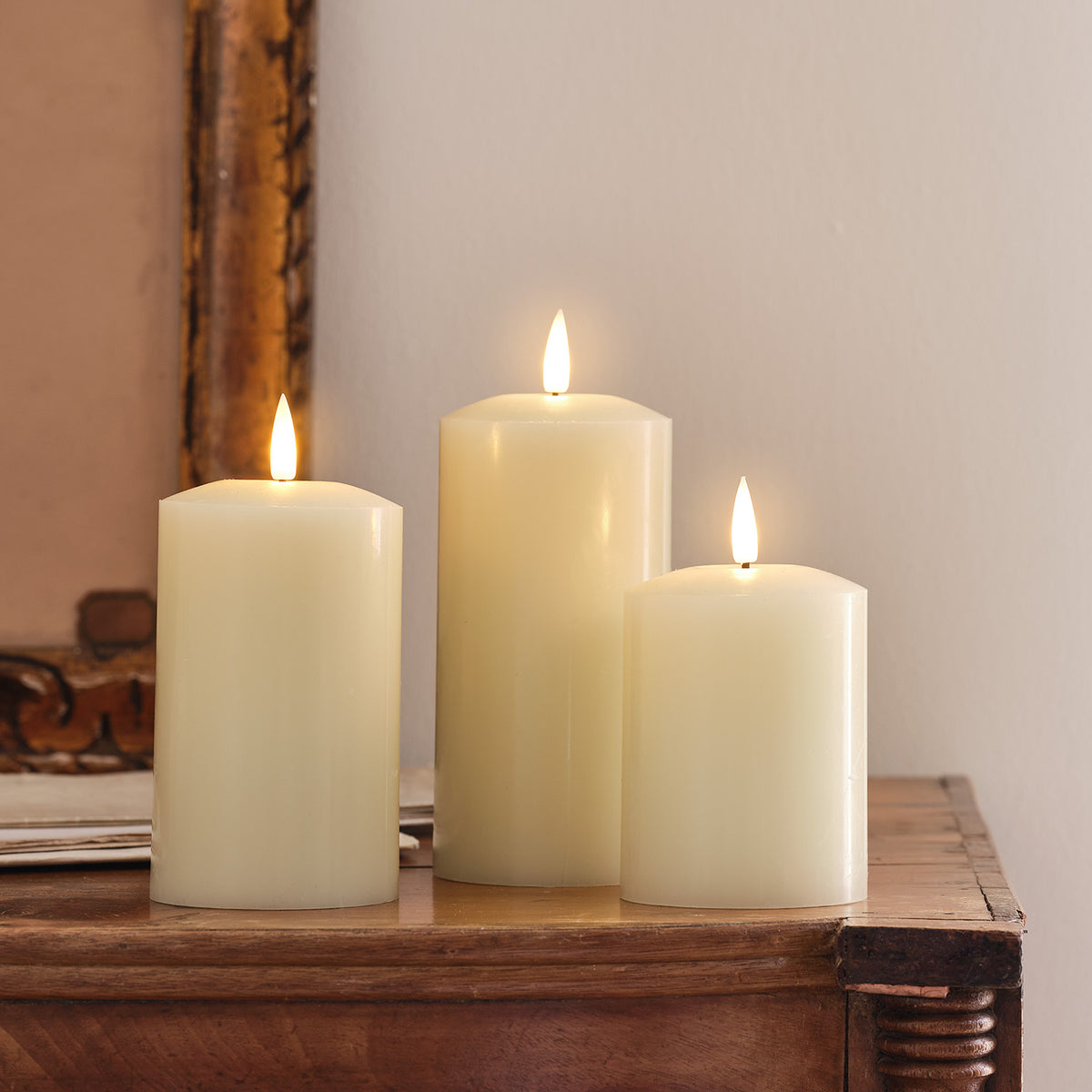 LED-Kerzen-Trio auf einem festlich gedeckten Holztisch mit Gläsern und Deko