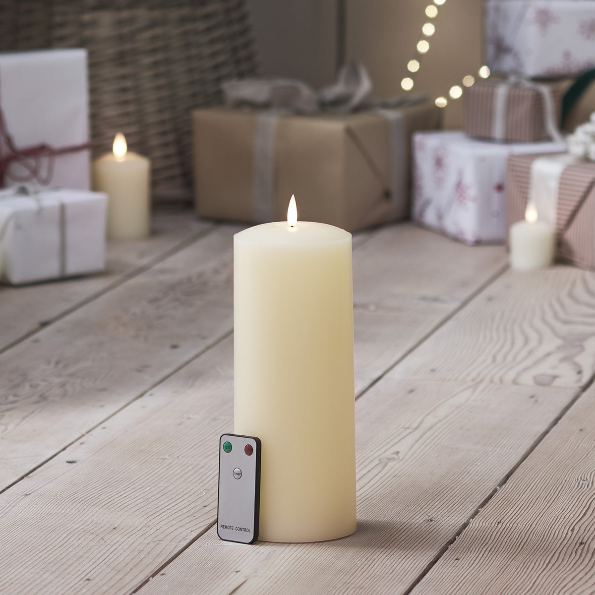 TruGlow LED Stumpenkerze mit Fernbedienung auf hellem Holzboden vor Weihnachtsdeko