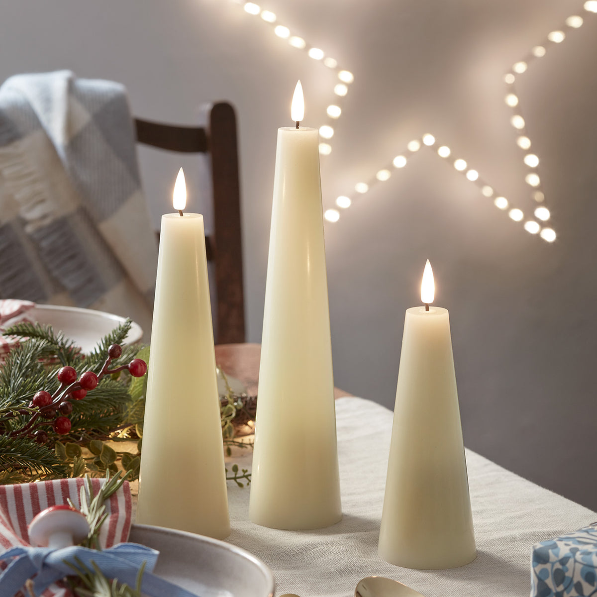Drei LED-Kerzen in Kegelform mit Fernbedienung auf festlich dekoriertem Tisch