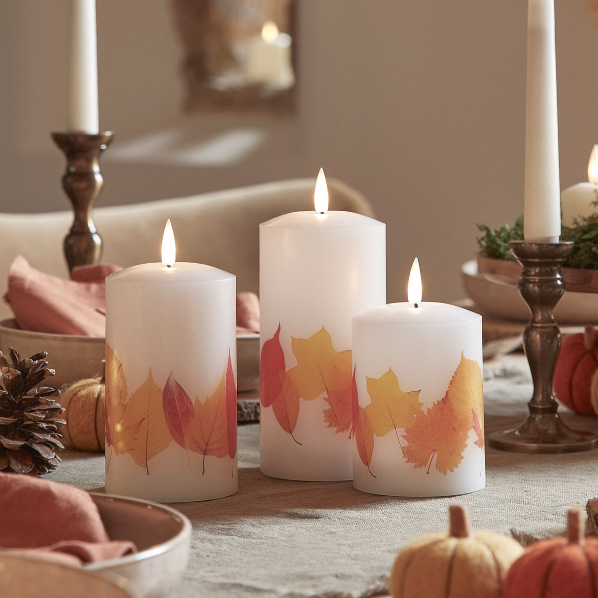 Nahaufnahme von drei LED Kerzen mit Herbstblättern in herbstlicher Tischdekoration