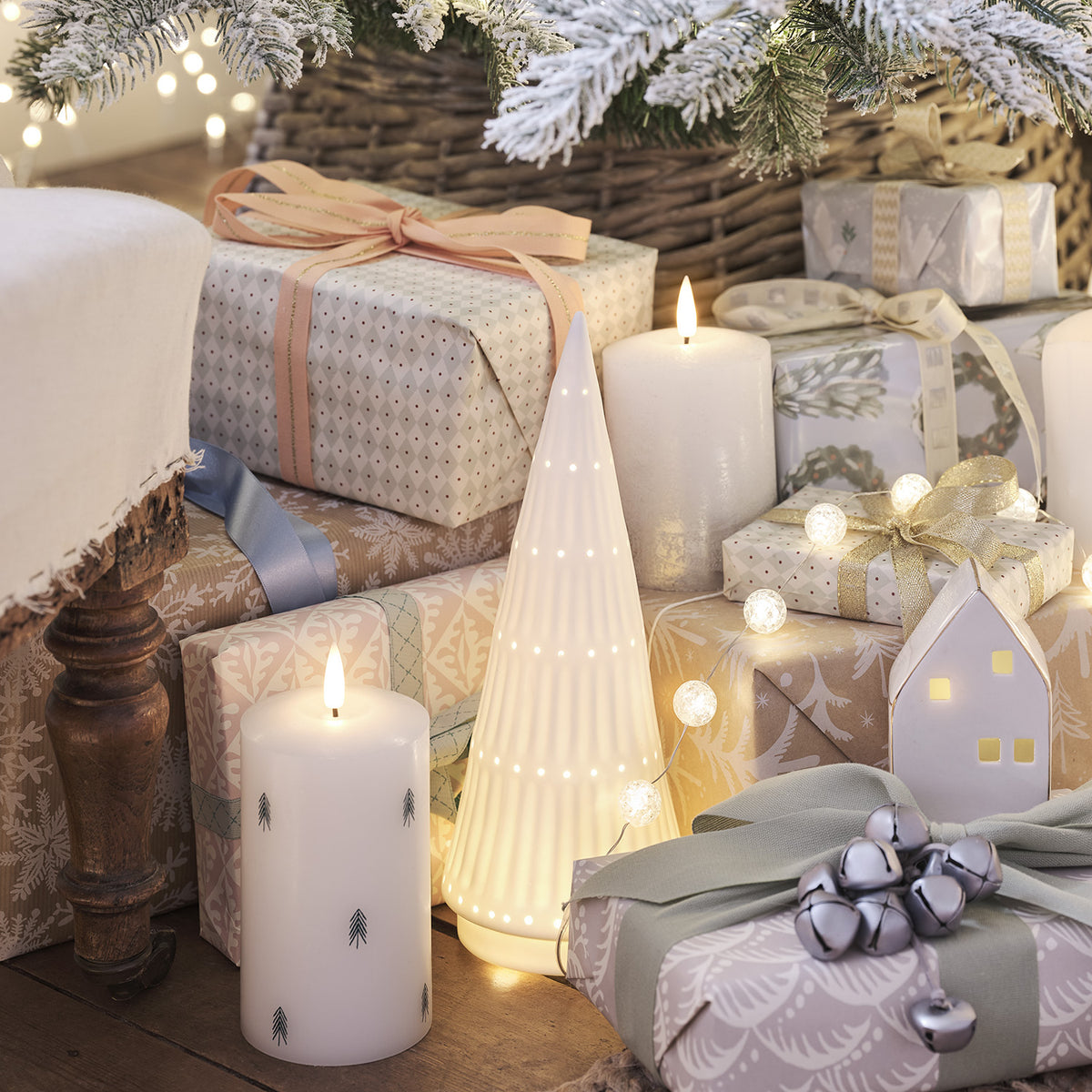 Silber ombré LED Kerze zwischen Weihnachtsgeschenken und Deko auf Holztisch