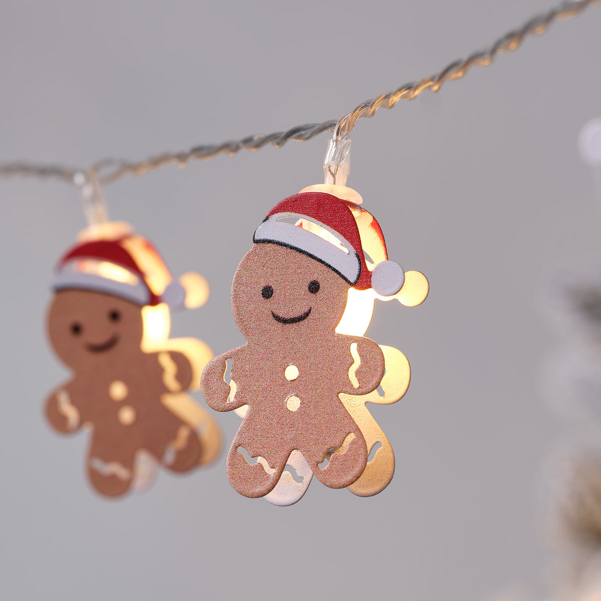 Nahaufnahme eines leuchtenden Lebkuchenmännchens mit roter Weihnachtsmütze an Lichterkette