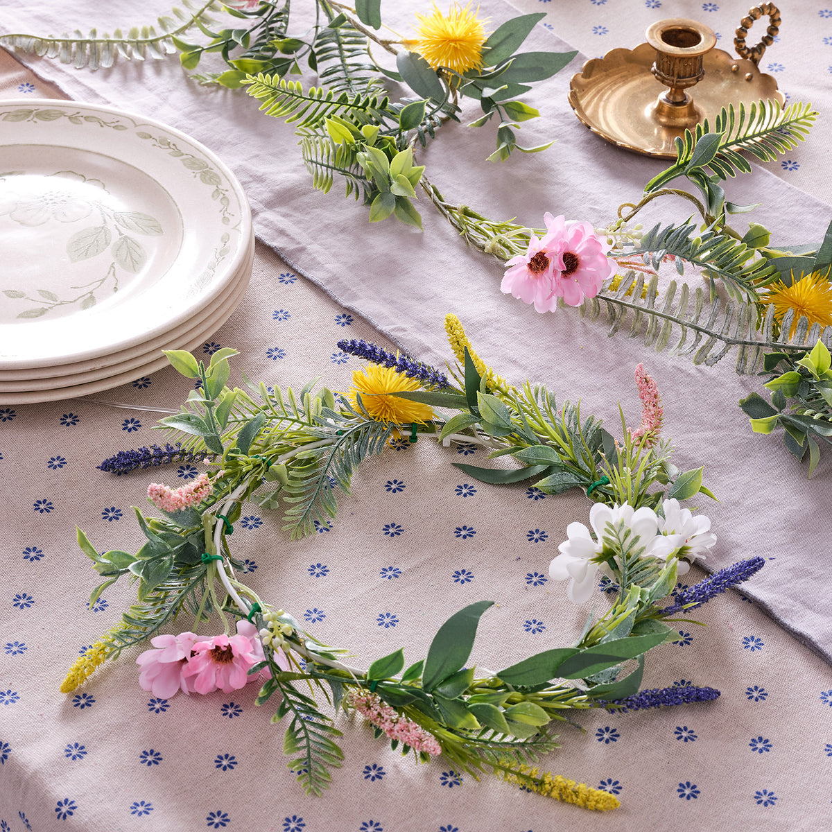 Nahaufnahme des beleuchteten Frühlingskranzes mit verschiedenen Blumen und Blättern auf Stoff