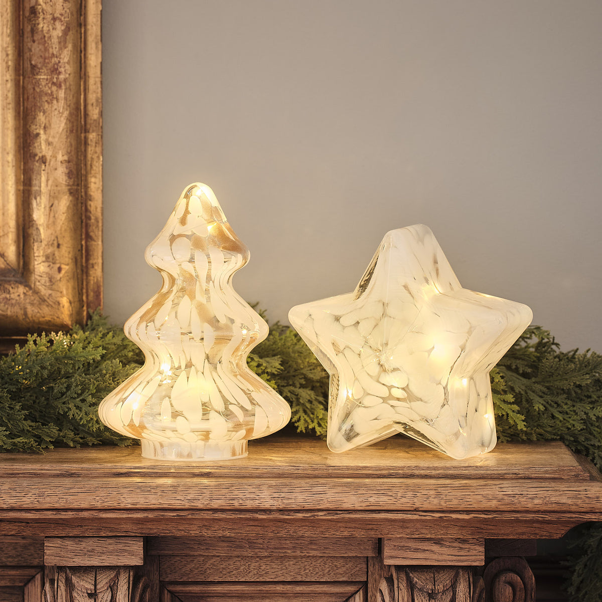 LED-Deko-Weihnachtsbaum und leuchtender Stern aus Konfetti-Glas auf Holz mit Tannengrün