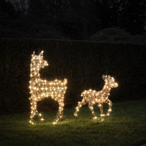 LED-Rentier Hirschkuh und Rehkitz in warmweiß leuchtend im Garten vor Hecke bei Nacht