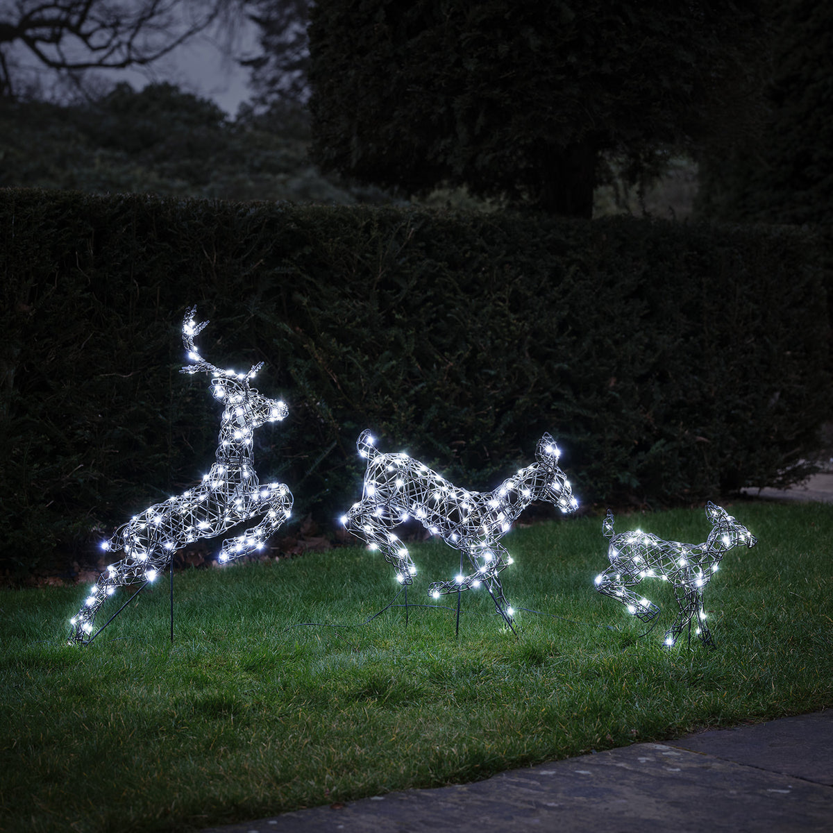 3er Set springende LED-Rentierfamilie mit kaltweißen Lichtern auf grünem Rasen bei Nacht