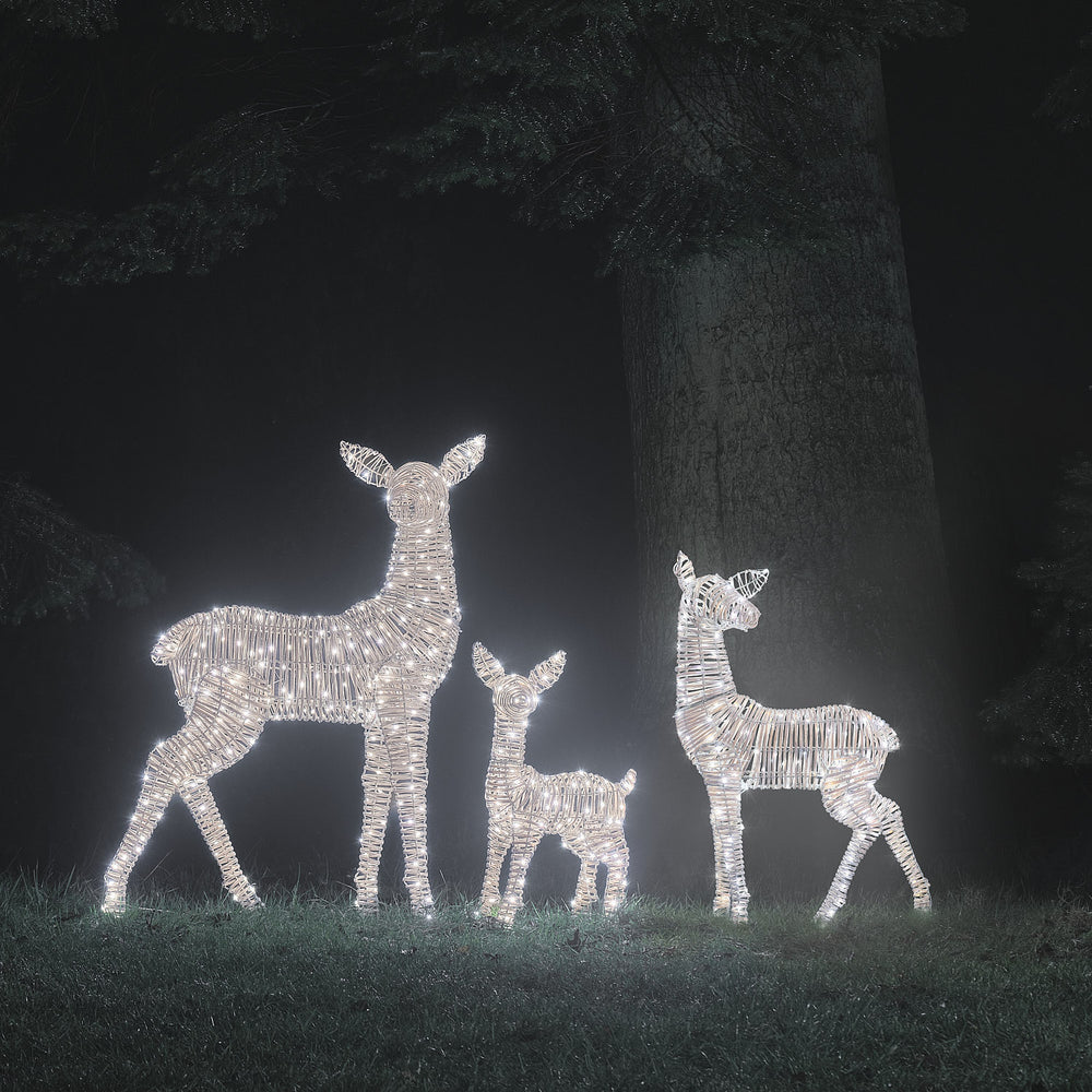 LED-Rentierfamilie in kaltem Weißlicht leuchtend vor dunklem Baum