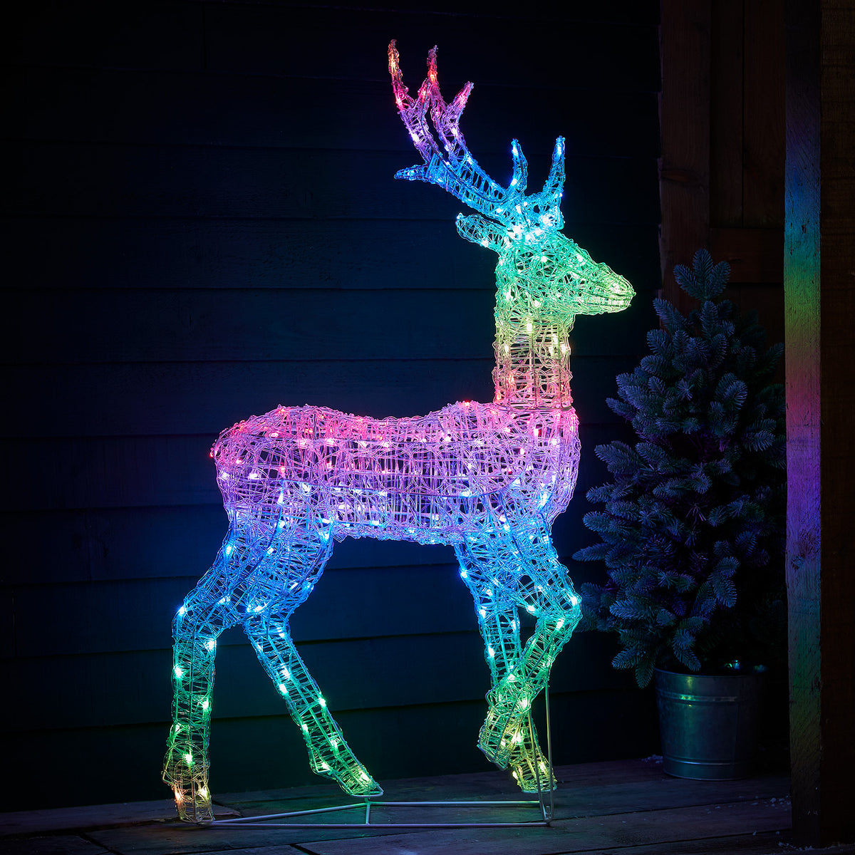LED-Hirsch weiß leuchtend vor dunkler Holzfassade auf Holzterrasse