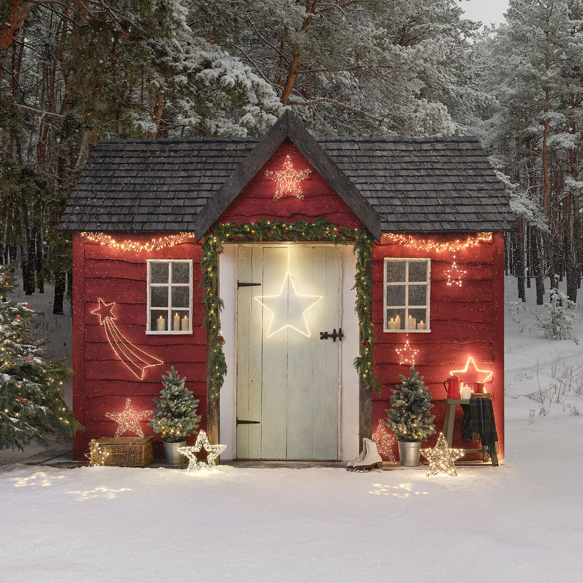 Rotes Gartenhäuschen mit verschiedenen LED-Sternen und Weihnachtsdeko im Schnee