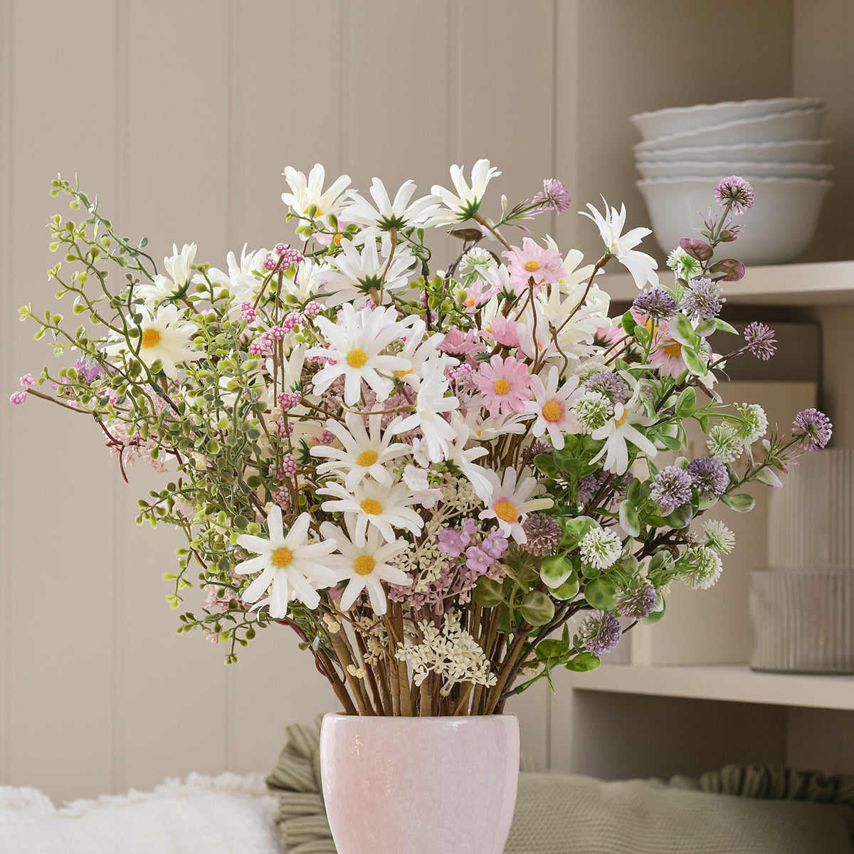 Nahaufnahme von künstlichen Gänseblümchen und Wildblumen in rosa-weißer Keramikvase