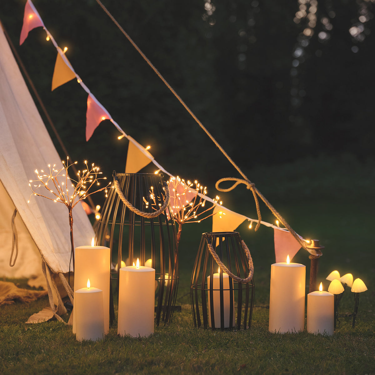 Drei Solar Feuerwerk Gartenstecker mit warmweißen LEDs neben Kerzen und Laternen im Garten