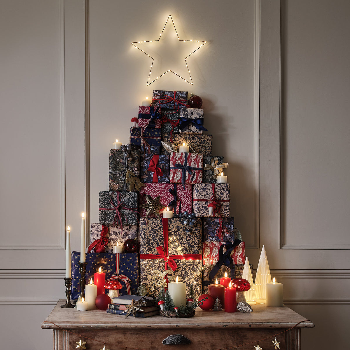 Weihnachtliche Dekoration mit Geschenken, Kerzen und Kerzenkranz mit Pilzen und Tannen