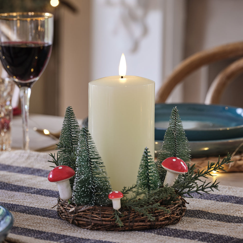 Winterlicher Rattan-Kerzenhalter mit Pilzdeko, Mini-Tannen und TruGlow LED-Kerze auf gedecktem Tisch