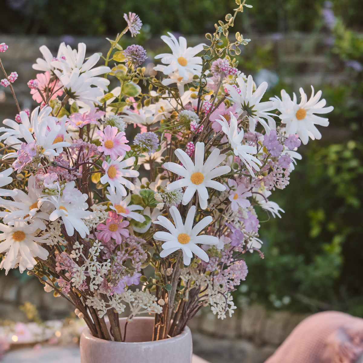 Nahaufnahme künstlicher Frühlingsstrauß mit weißen Gänseblümchen und rosa Wildblumen im Garten