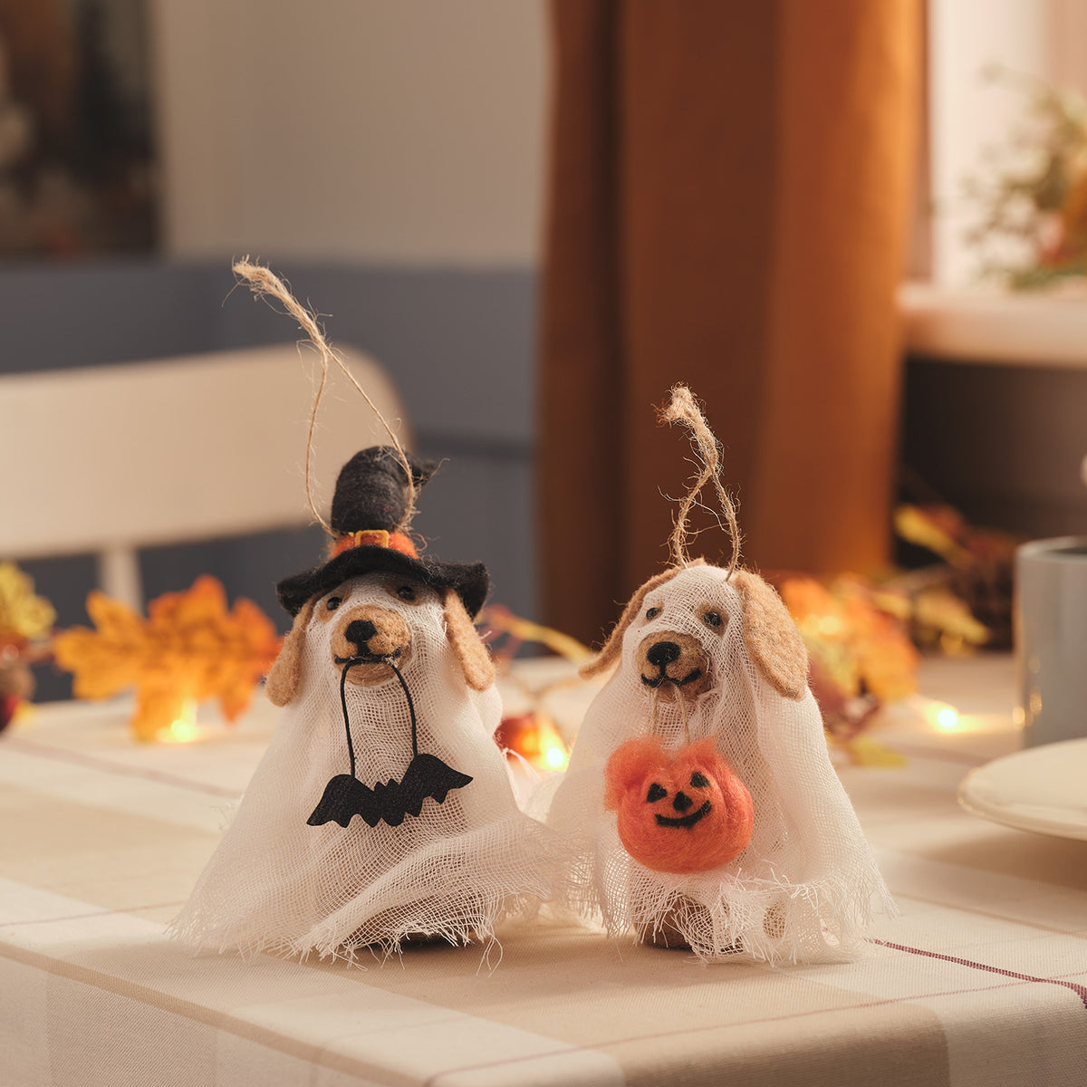 Zwei hängende Geisterhunde aus Filz mit Halloween-Deko, einer mit Hexenhut und Fledermaus, der andere mit Kürbis