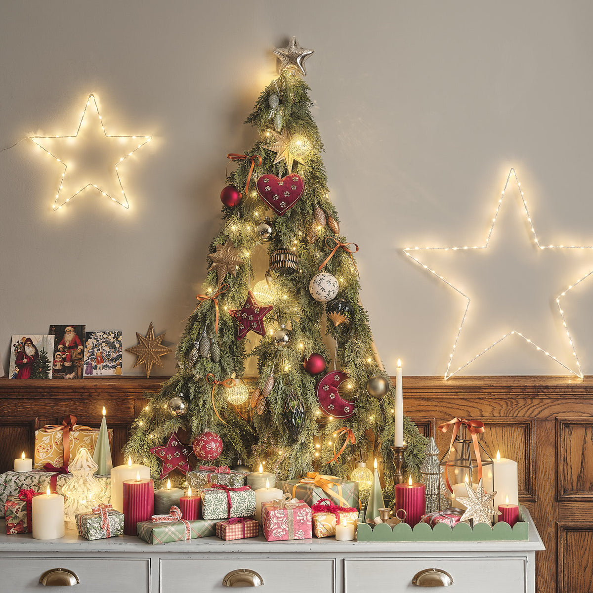 Weihnachtsbaum mit LED-Kugeln, Sternen und Kerzen, dekorativ beleuchtet in einem Raum