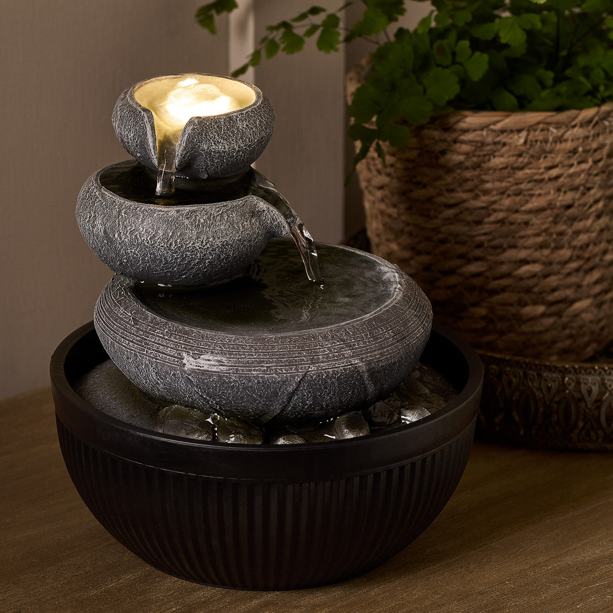 Nahaufnahme des grauen Zimmerbrunnens mit fließendem Wasser und LED-Licht