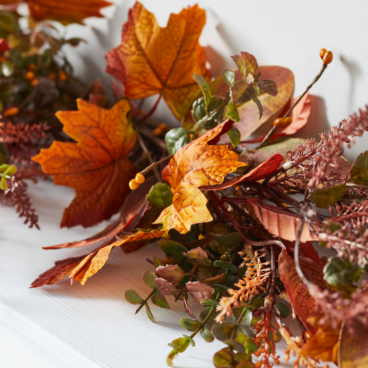 Nahaufnahme der herbstlichen Girlande mit orangefarbenen Ahornblättern und grünen Zweigen