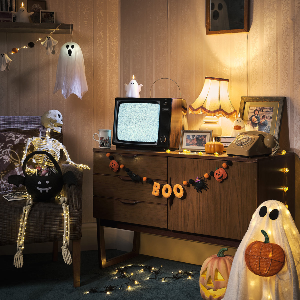 Halloween-Deko mit LED Geist, Skelett, Kürbissen und Girlanden in einem Wohnzimmer