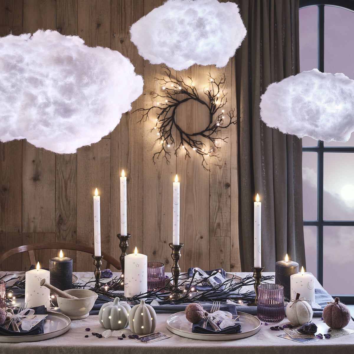 Halloweenkranz mit LEDs an Holzwand über gedecktem Tisch mit Kerzen und Dekoration