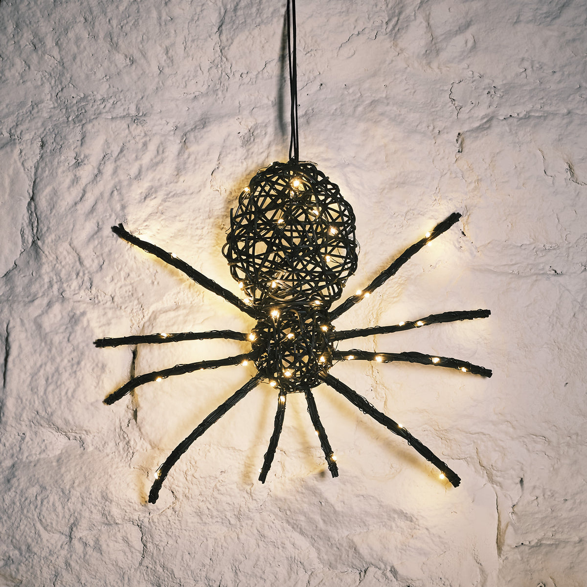 Nahaufnahme der LED Rattan Spinne mit warmweißen Lichtern an weißer Wand