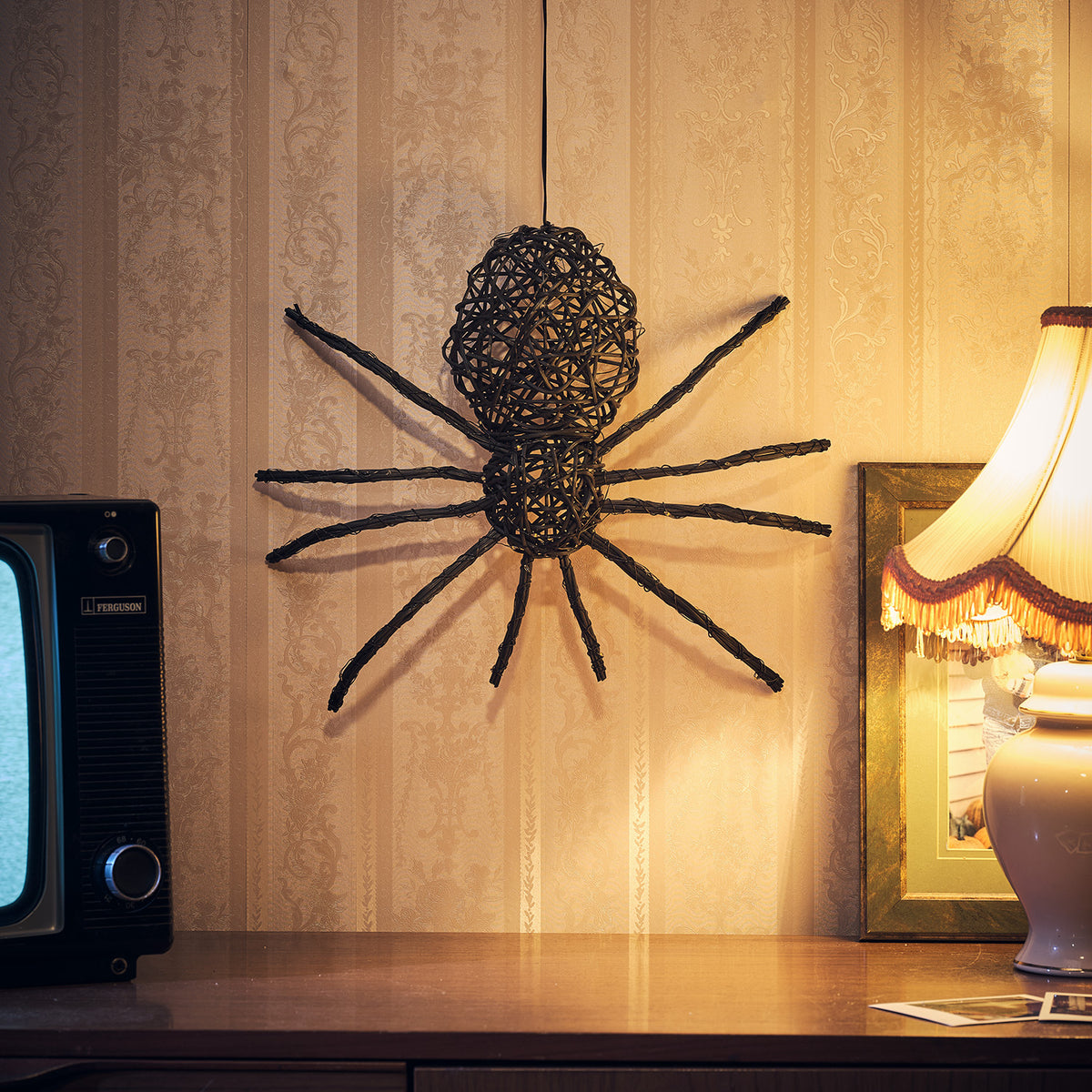 LED Rattan Spinne ohne Beleuchtung an Wand über Kommode mit Lampe und Fernseher