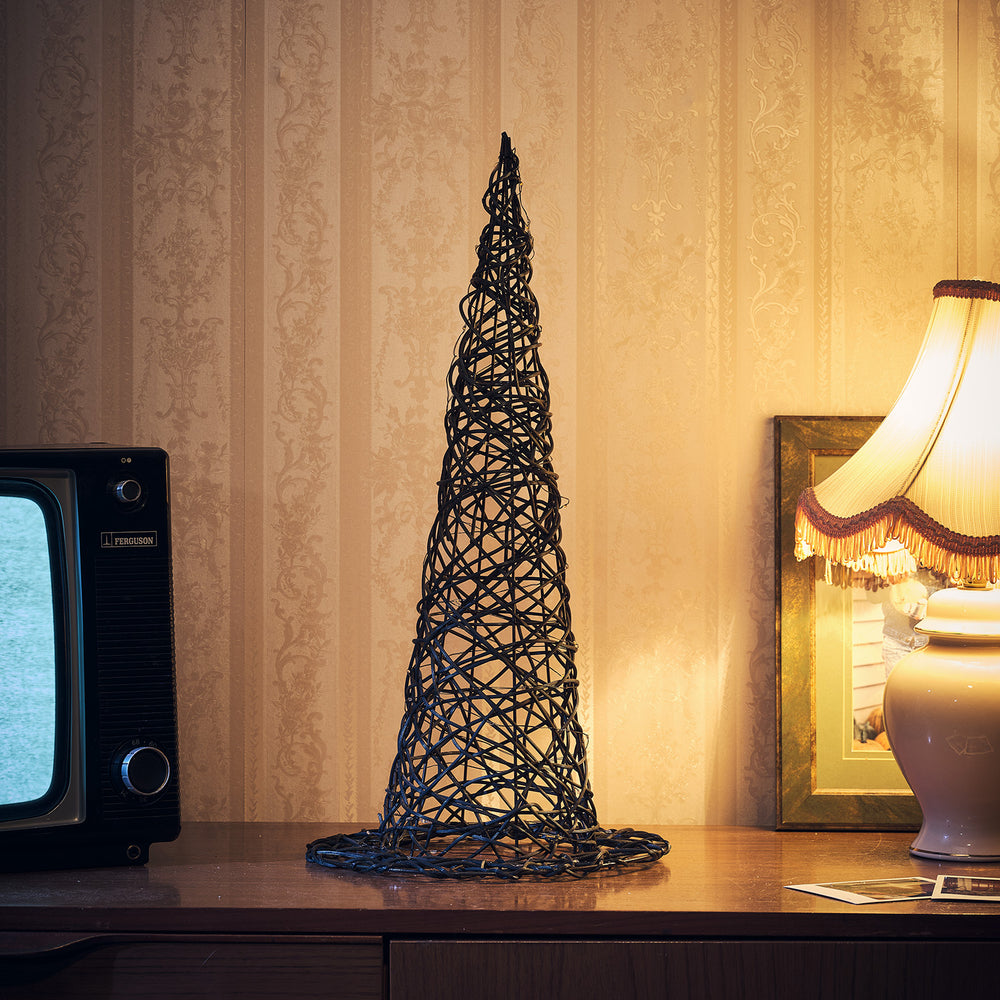 Rattan Hexenhut ohne Beleuchtung auf Holztisch vor gemusterter Tapete neben Lampe und Fernseher