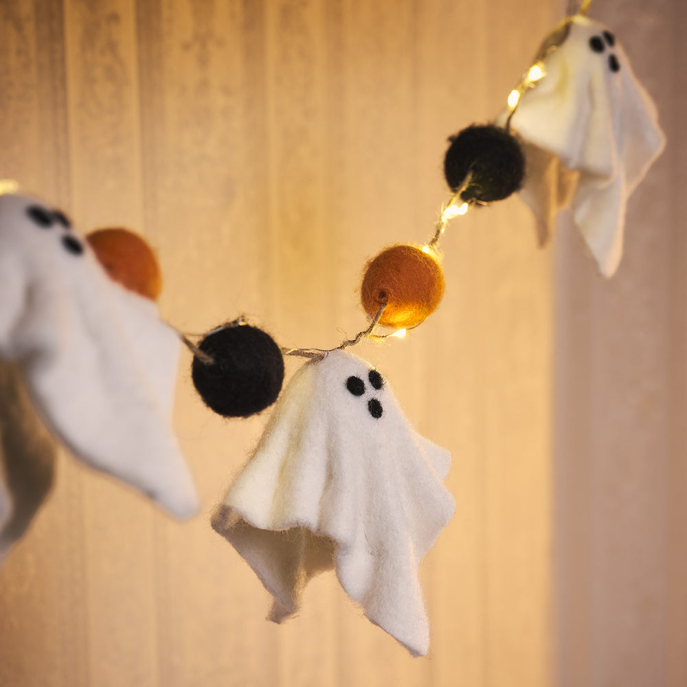 Halloween Lichterkette mit weißen Filzgeistern und schwarzen sowie orangefarbenen Pompons, warmweiße LEDs
