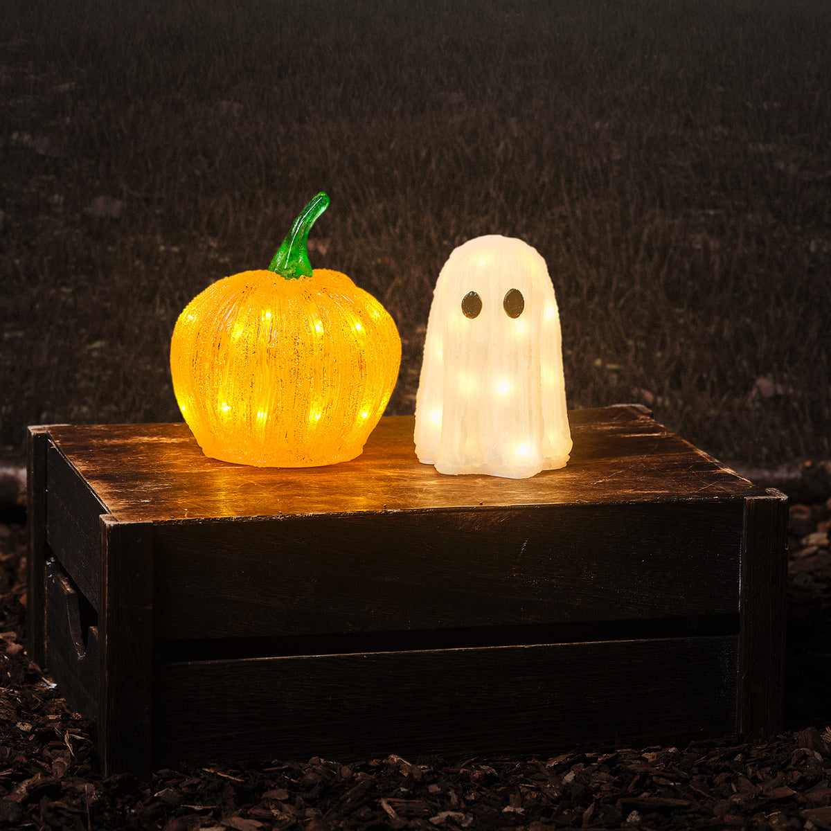 Leucht-Set Geist warmweiß und Mini-Kürbis orange leuchtend auf Holzkiste vor dunklem Hintergrund