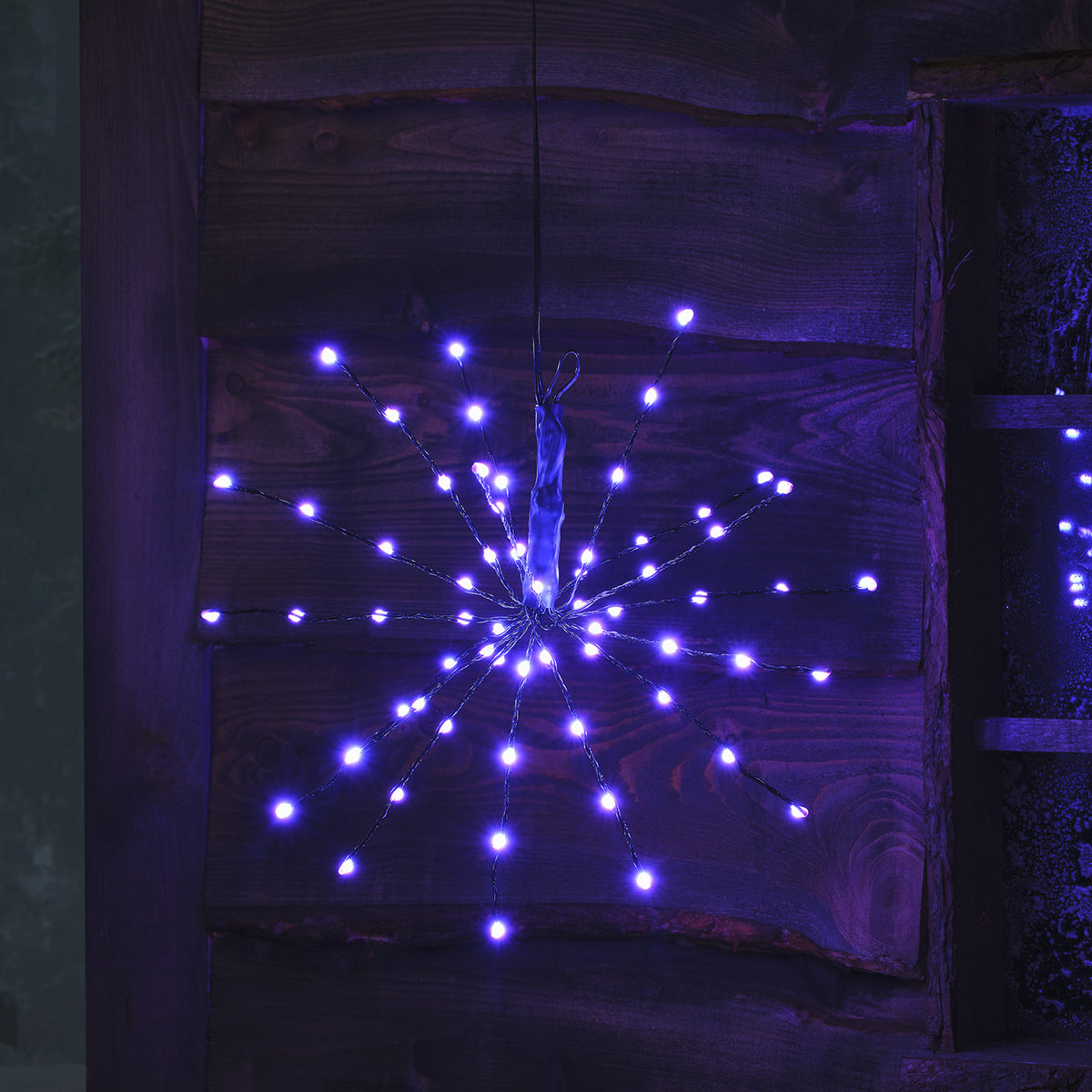 LED Starburst Weihnachtsdeko mit blauen LEDs an flexiblen Ästen vor Holz