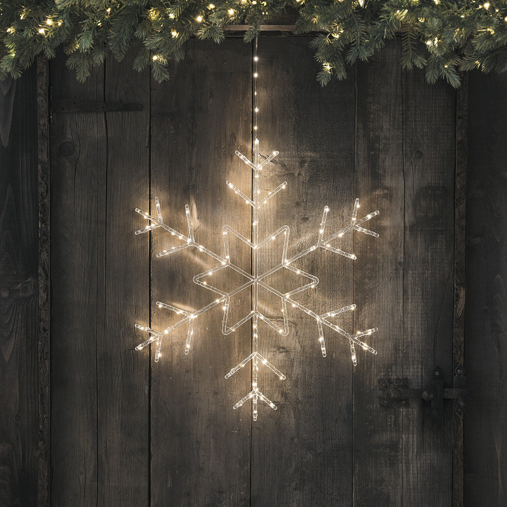 Leuchtende Acryl-Schneeflocke mit warmweißen LEDs an dunkler Holzwand