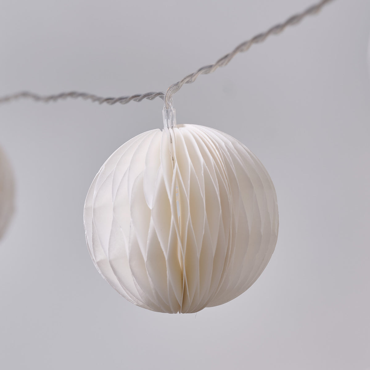 Weißer Papierlampion mit feiner Faltung an transparenter Kabel-Lichterkette