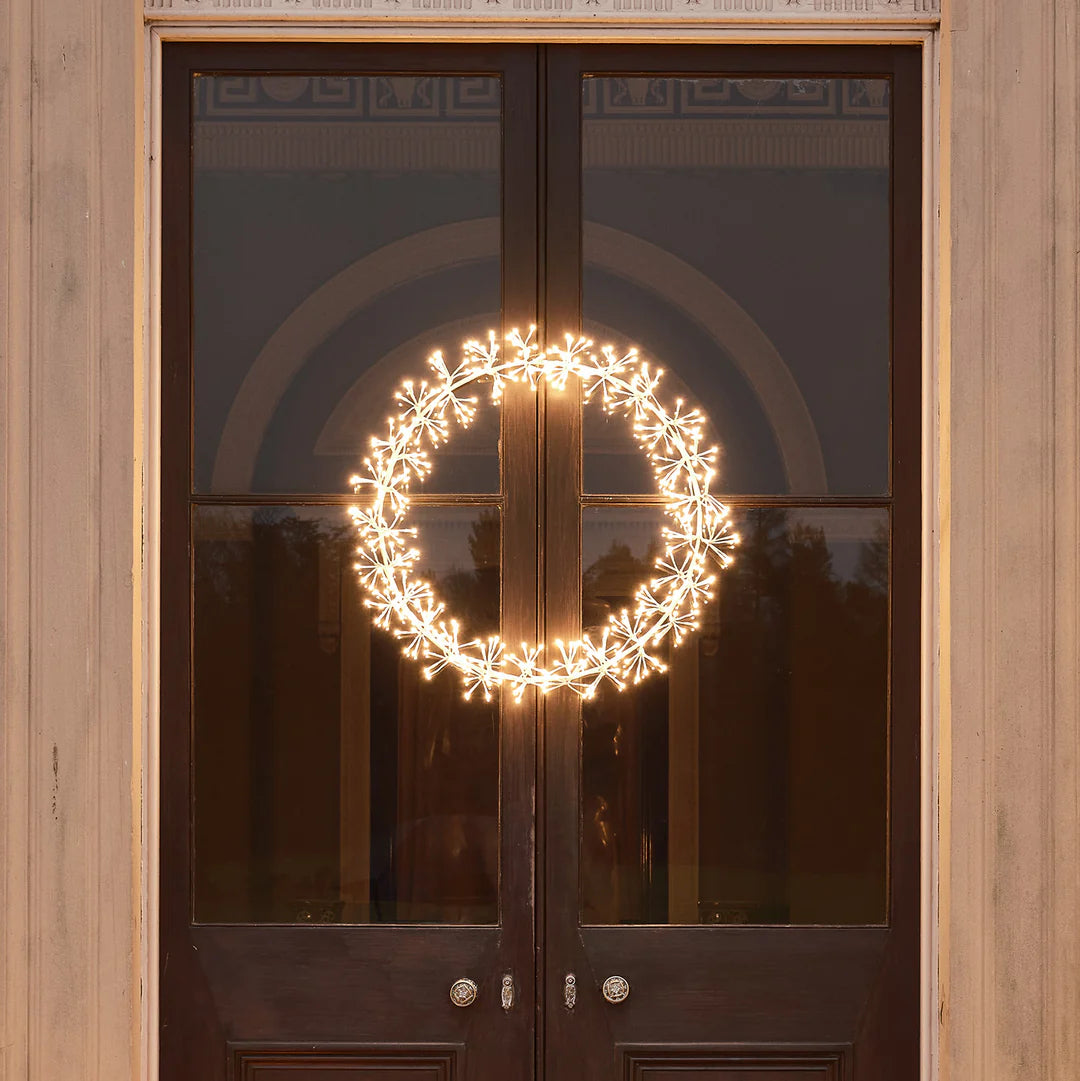 LED Weihnachtskranz mit warmweißen Stern-Clustern an dunkler Holztür