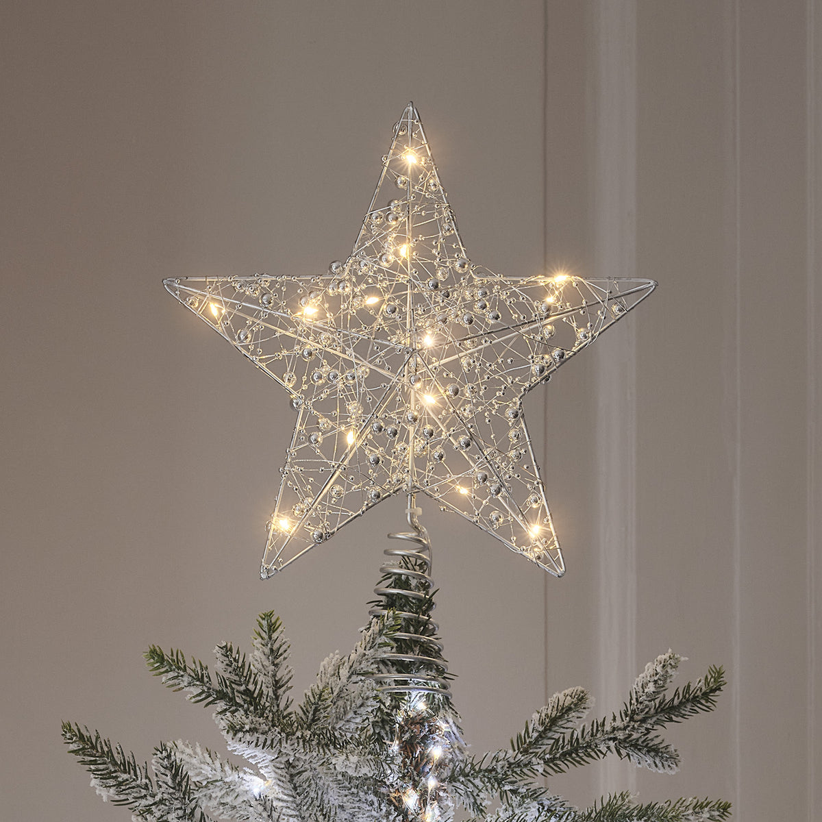 Nahaufnahme LED-Stern Weihnachtsbaumspitze mit silberfarbenem Draht und warmweißen LEDs