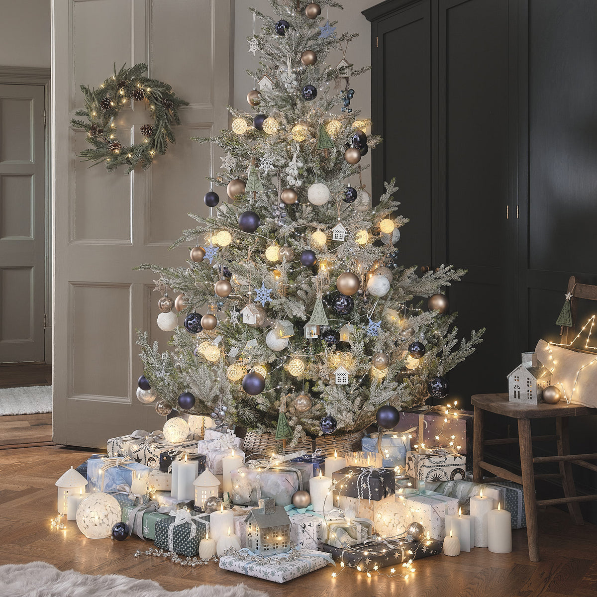 Beleuchteter Weihnachtsbaum mit Geschenken in gemütlichem Wohnzimmer.