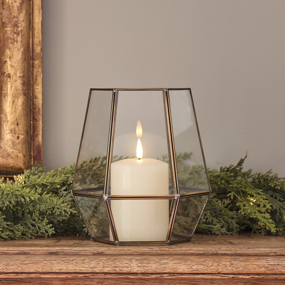 "Geometrische Glaslaterne mit LED-Kerze auf Holztisch vor Tannengrün.