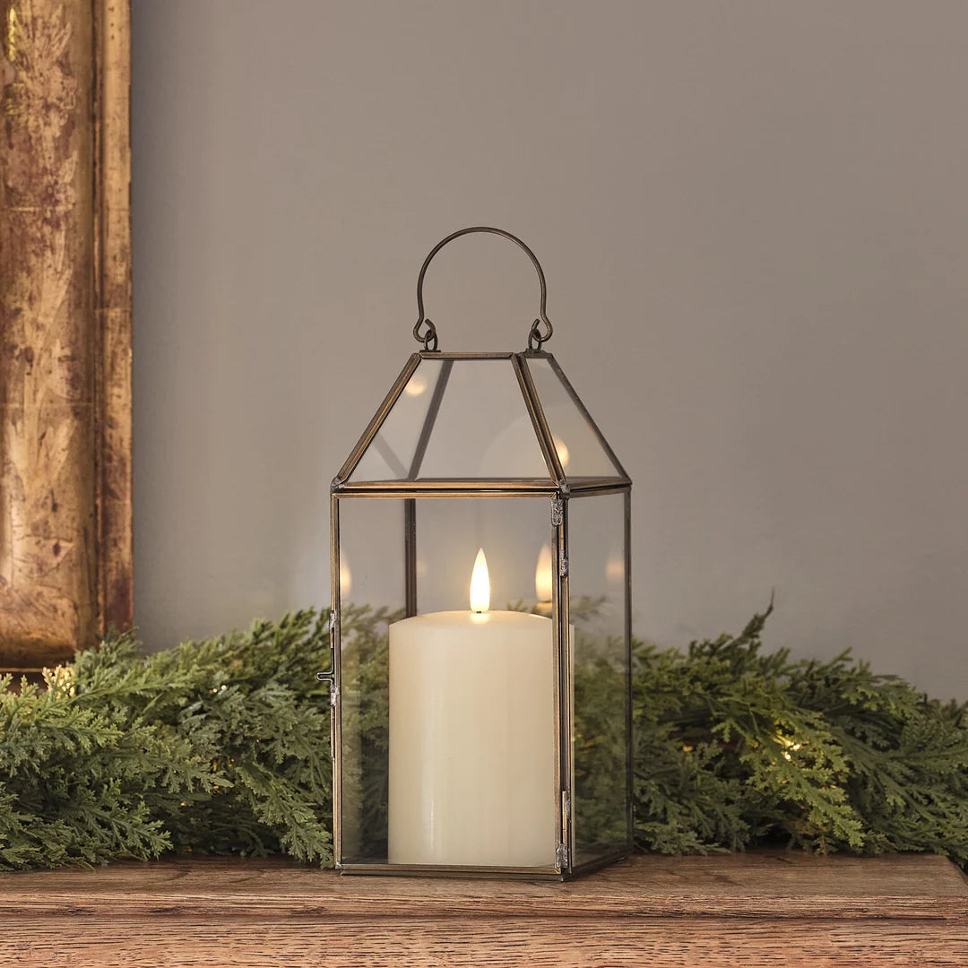 "Goldene Metall-Laterne mit LED-Kerze auf Holztisch vor Tannengrün.