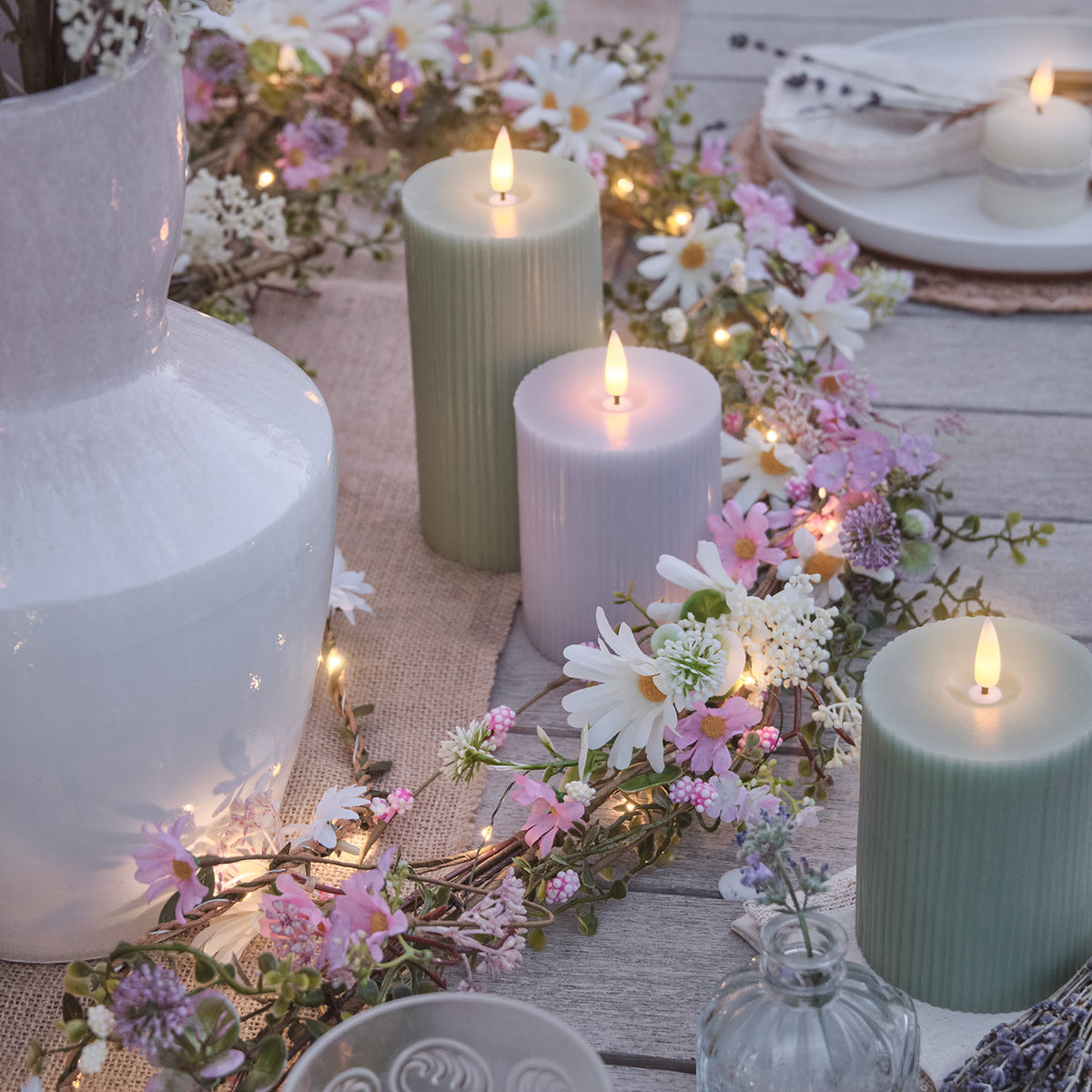 LED-Blumengirlande mit weißen Margeriten und rosa Blüten auf gedecktem Tisch