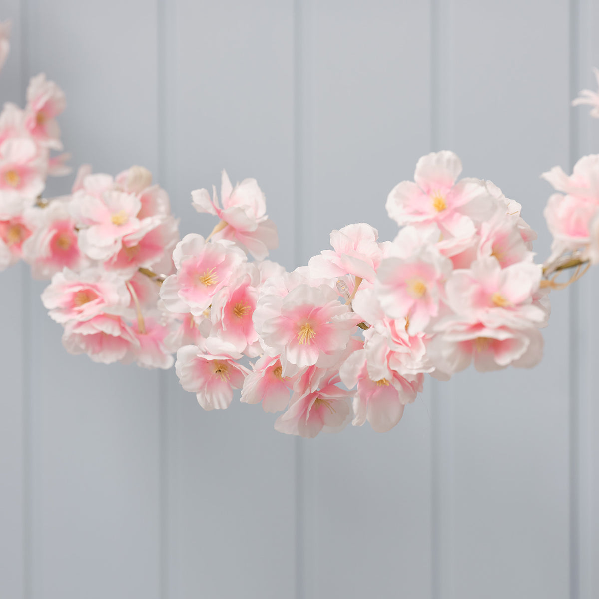 Nahaufnahme LED-Blumengirlande mit zarten rosa Blüten und warmweiß leuchtenden LEDs
