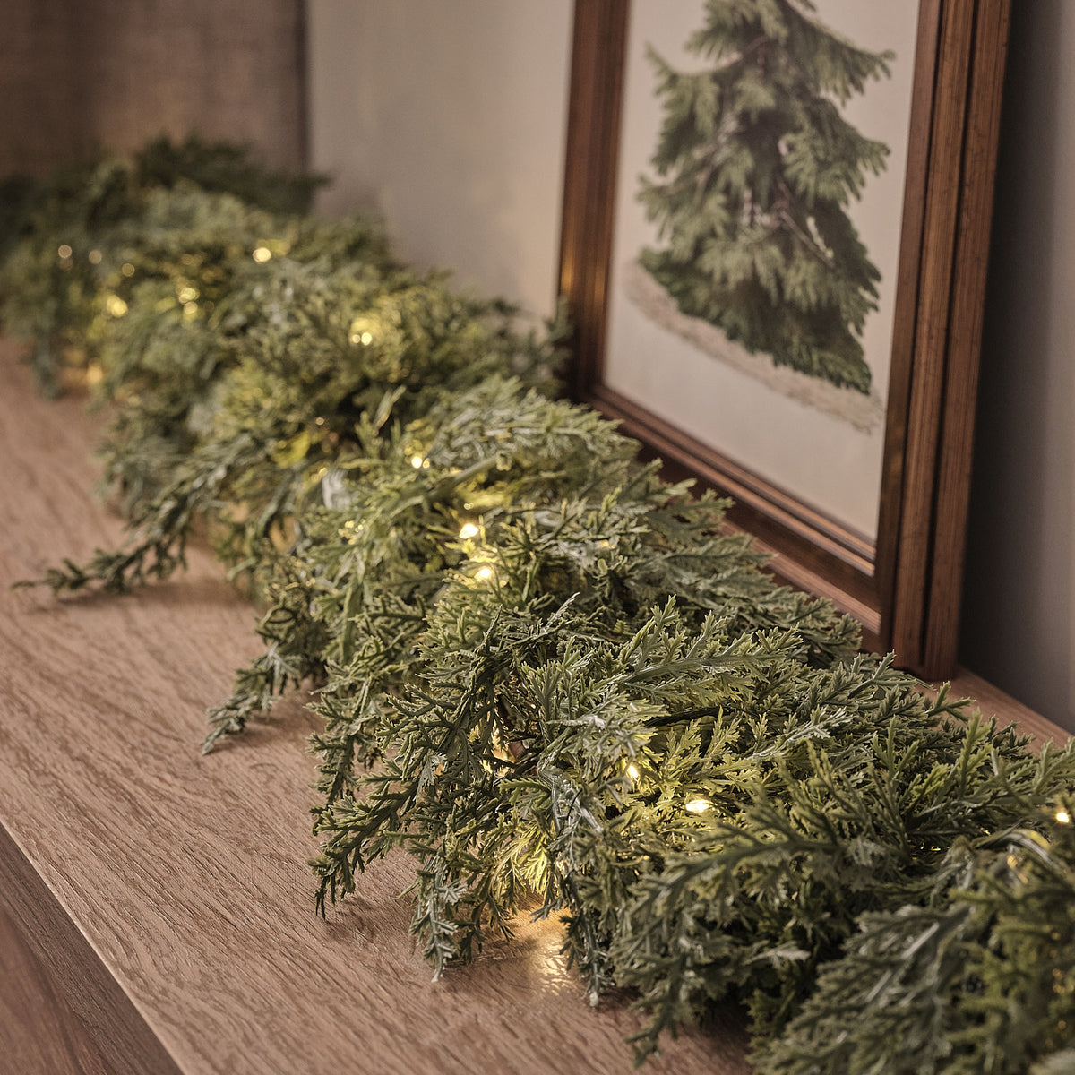 Beleuchtete Weihnachtsgirlande aus künstlichem Nadelgrün auf Holzkommode nahaufnahme