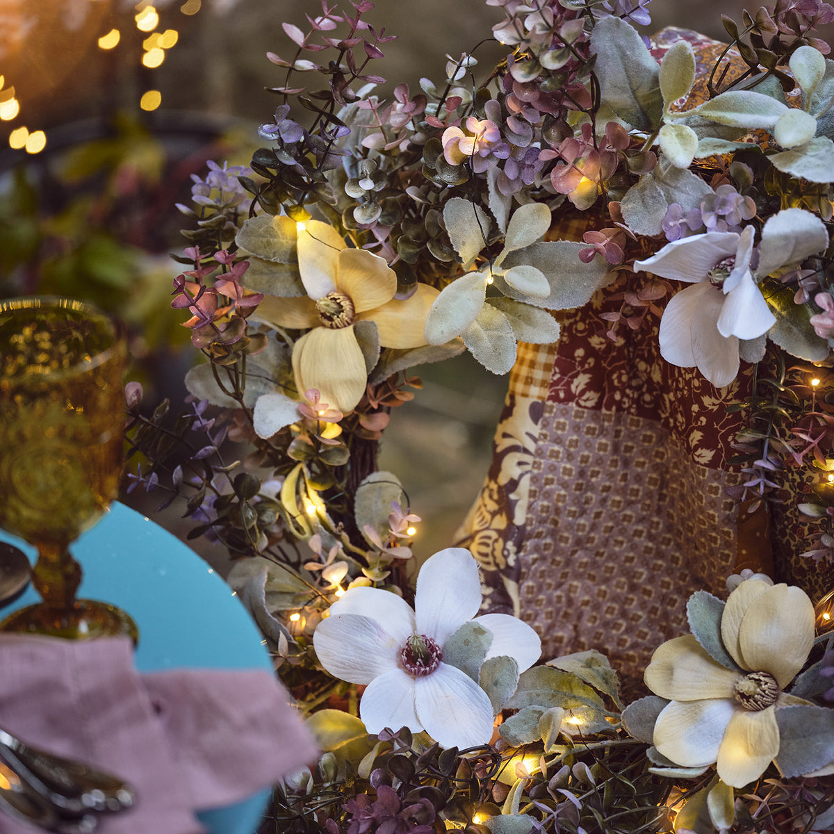 Nahaufnahme des Frühlingskranzes mit weißen und cremefarbenen Blumen und warmweißen Micro-LEDs