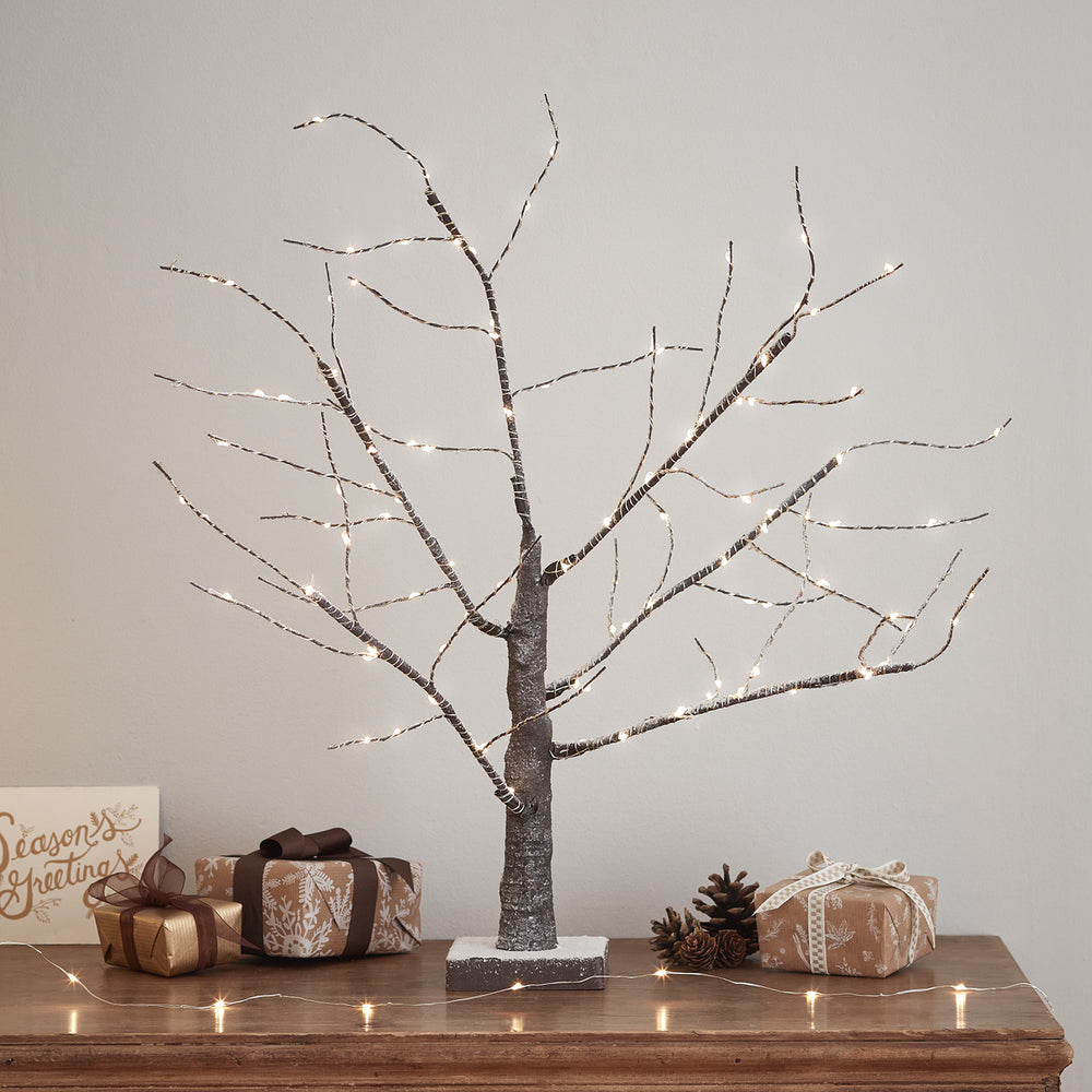 LED Baum mit 108 warmweißen Micro LEDs und Schnee auf Ästen, dekoriert mit Geschenken und Zapfen auf Holztisch
