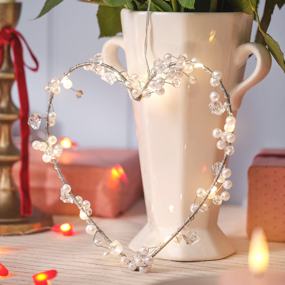 LED Herz Deko mit Perlen und warmweißen Micro LEDs vor weißer Vase auf Tisch