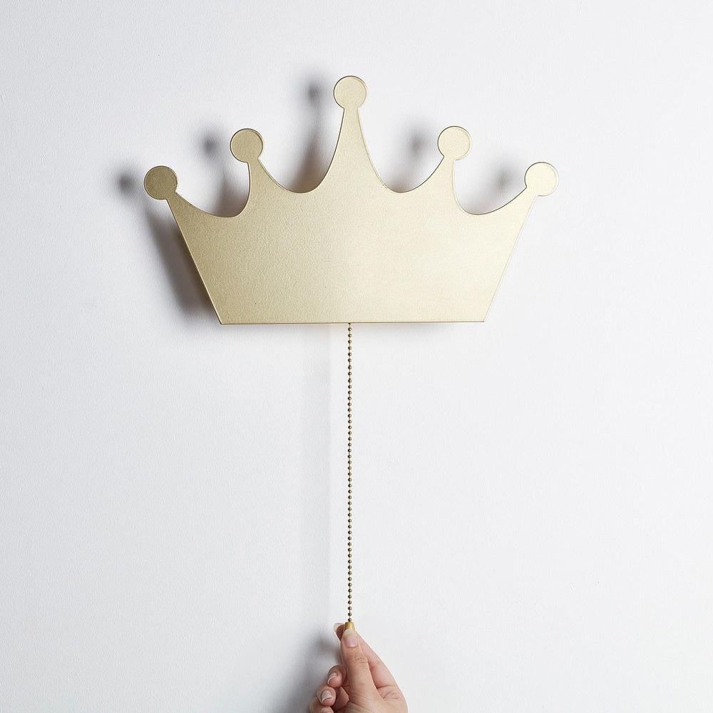Goldene Kronen-Wandlampe mit Zugkette, Hand zieht an Kette zum Einschalten