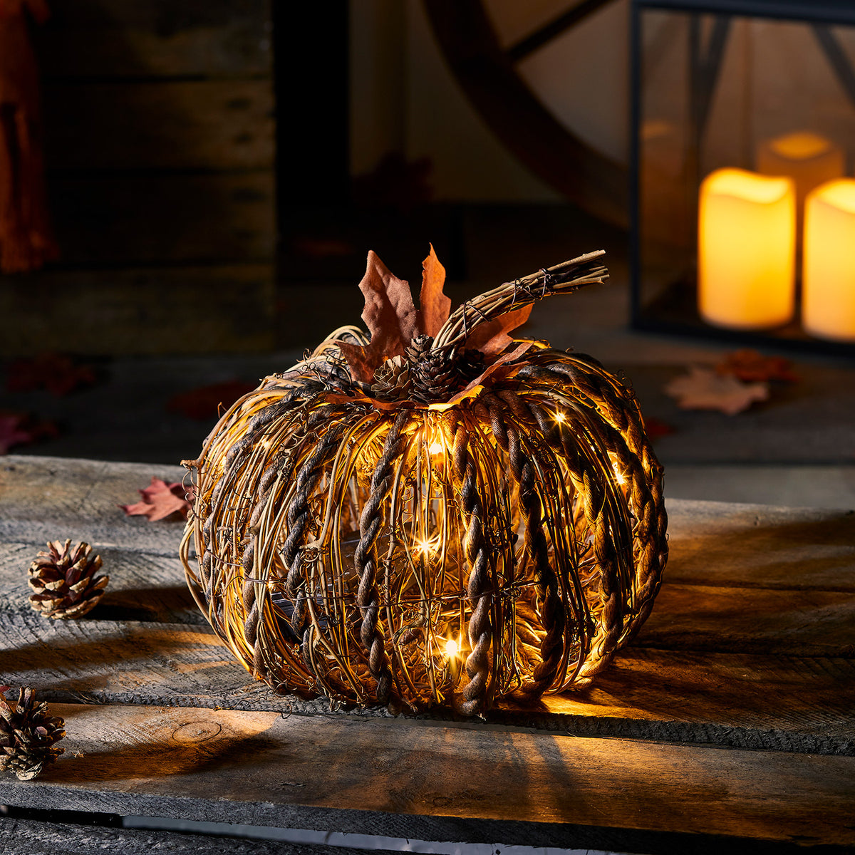 Nahaufnahme des beleuchteten Rattan-Kürbisses mit LED-Lichtern und Herbstdeko im Dunkeln
